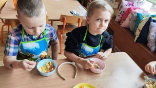 dzieci jedzą sałatkę owocową